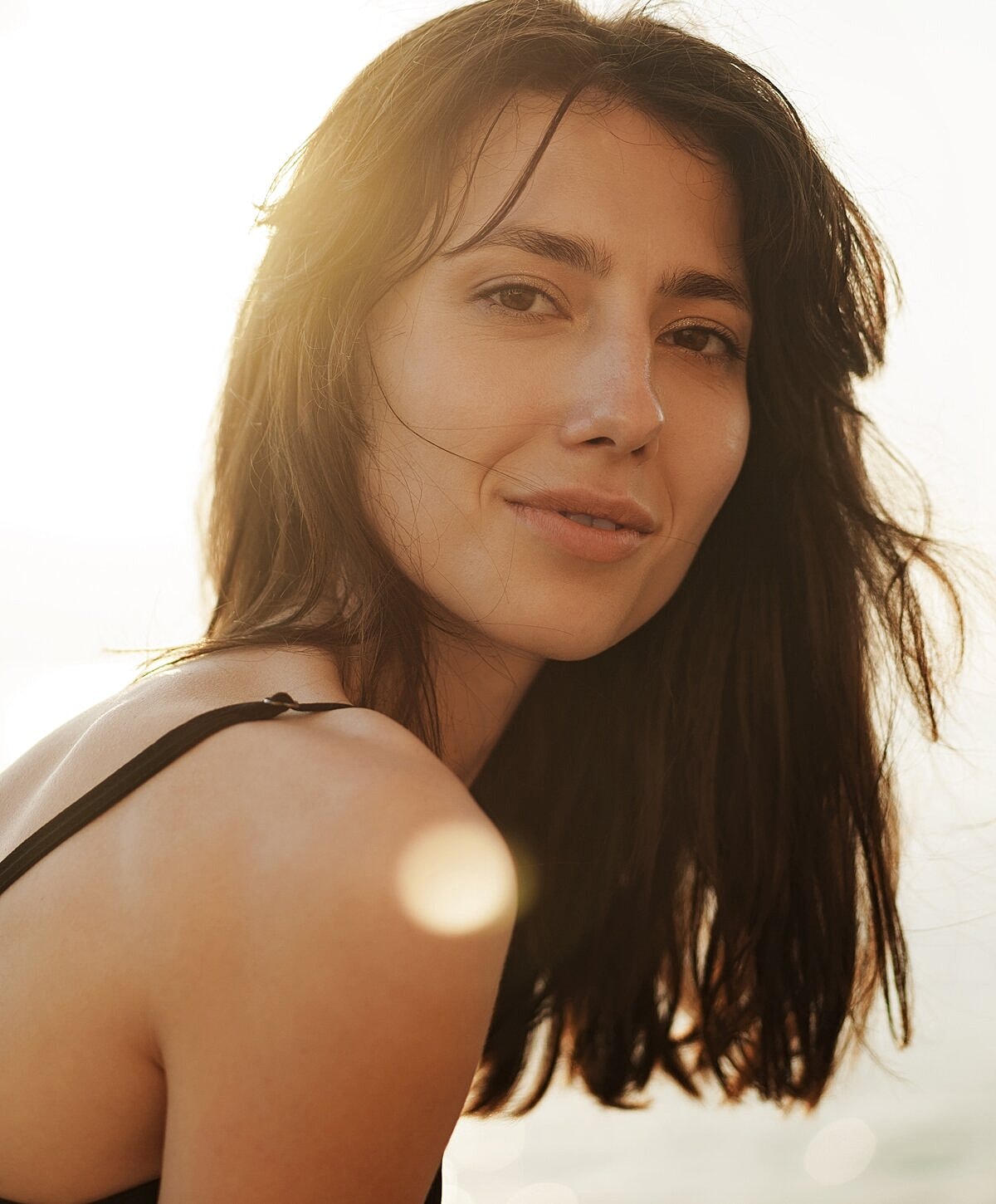 Woman with wet hair sitting on the beach.