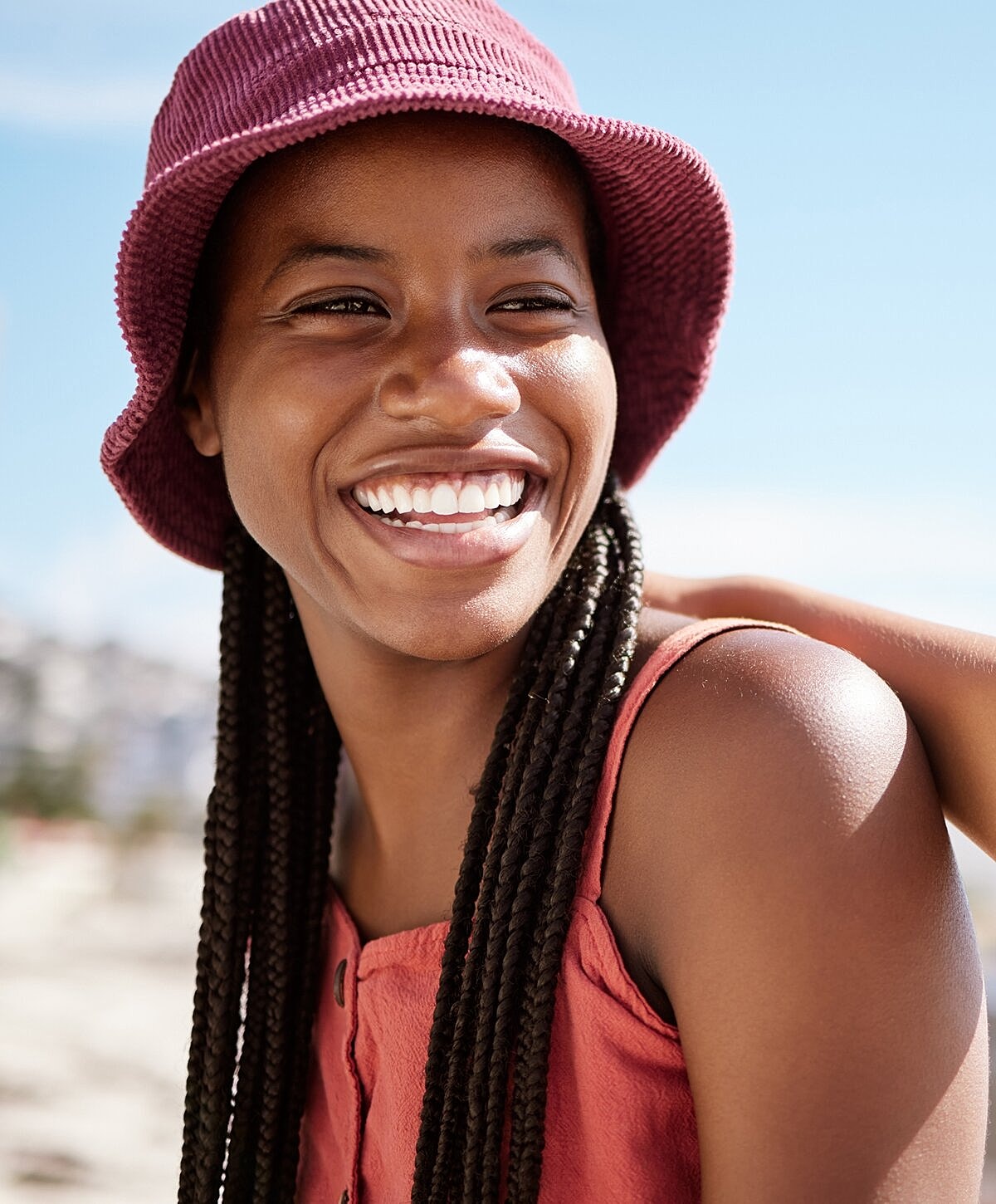 Smiling woman with braided hair and hat.
