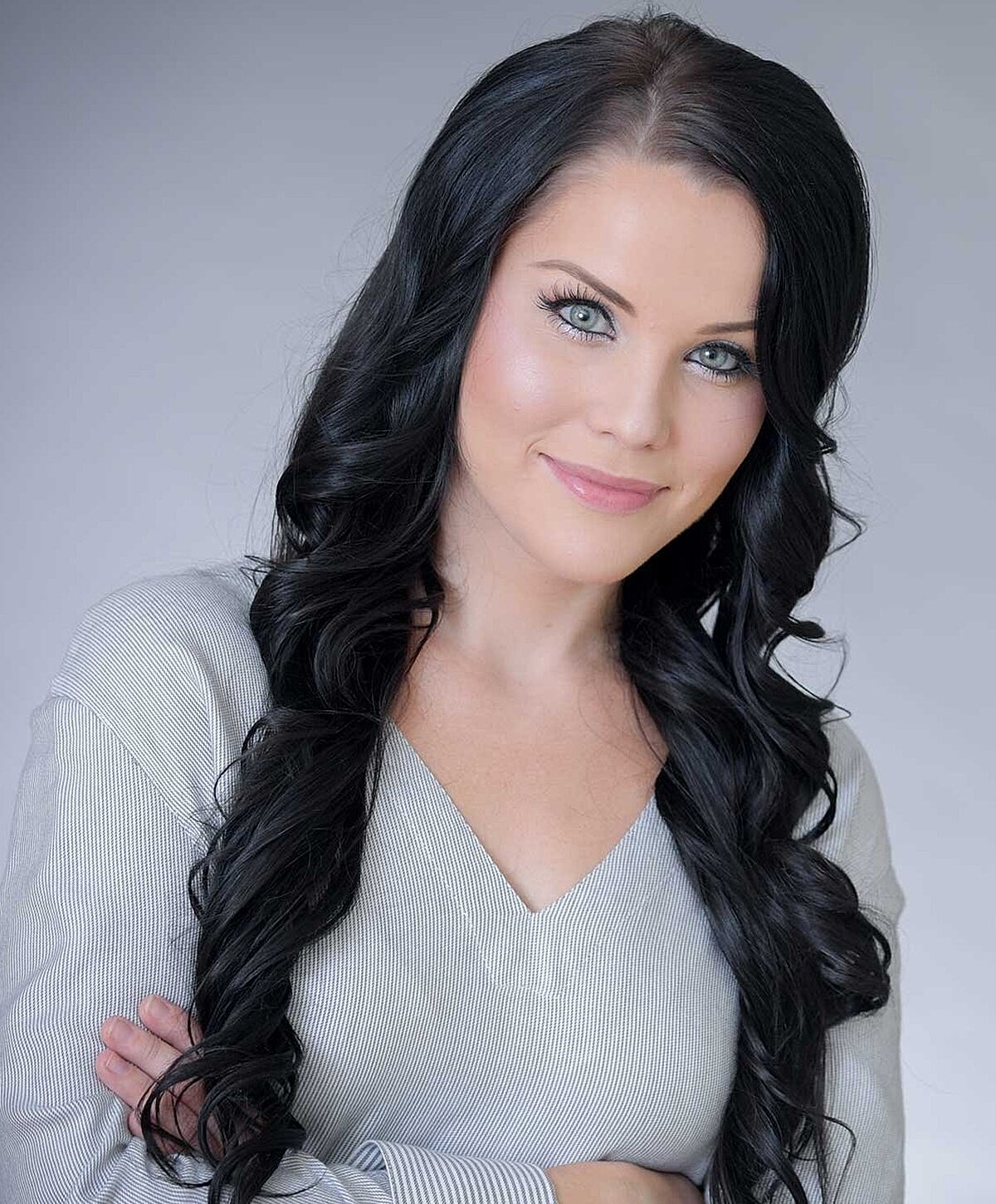Woman with long hair, smiling confidently.