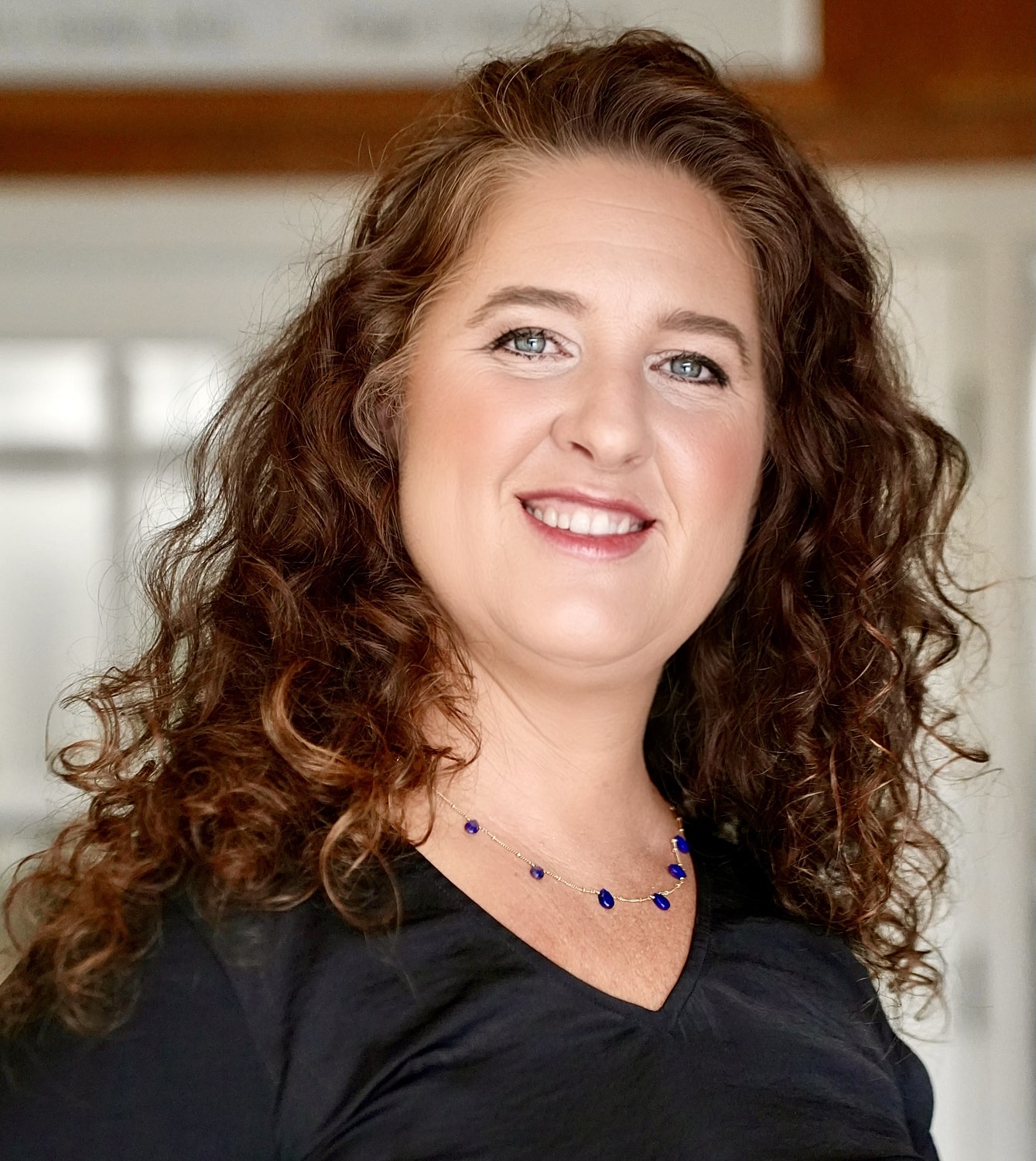 Woman with curly hair smiling at the camera.