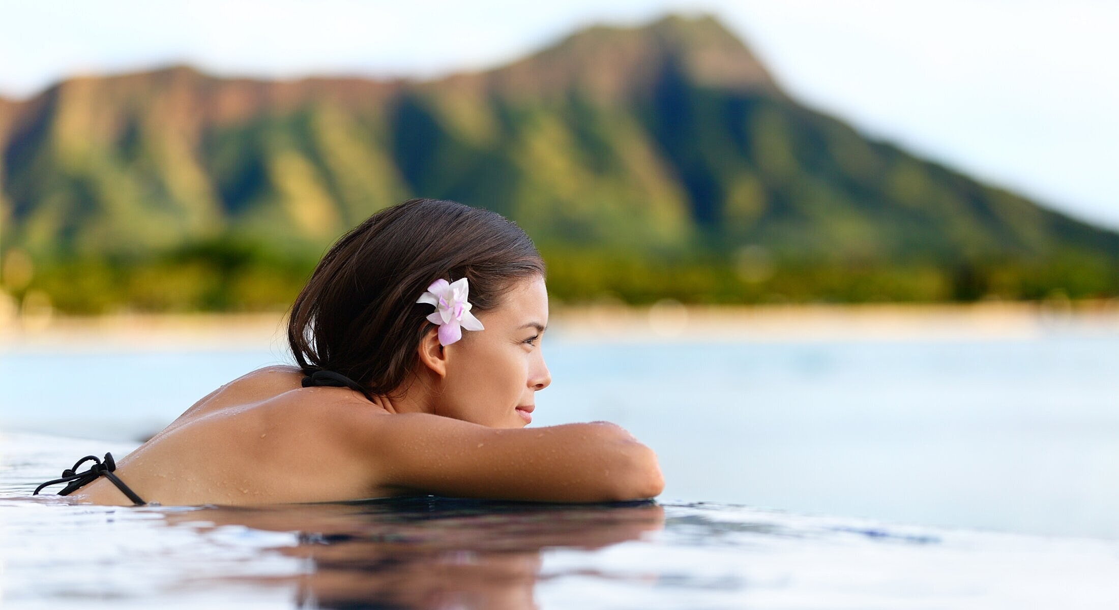 Woman relaxing in pool with mountain backdrop.