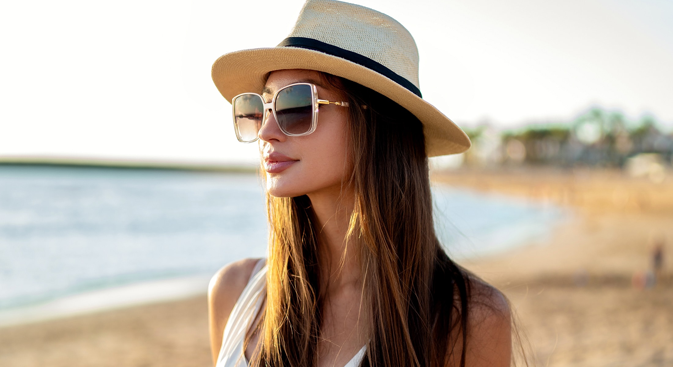 Woman wearing hat and sunglasses at beach.